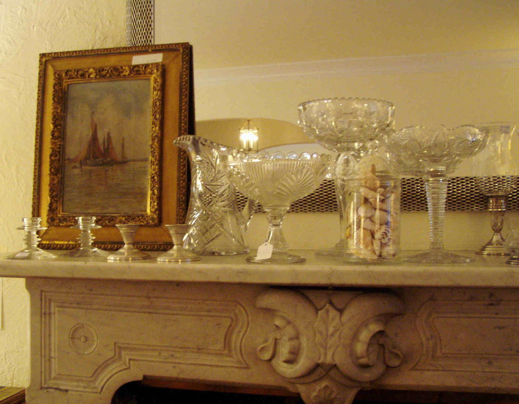 Antique framed artwork and glassware displayed for an estate sale